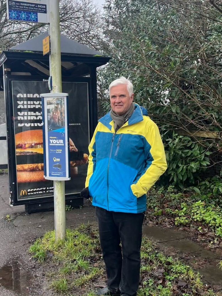 Man at bus stop, hoping for better disabled access