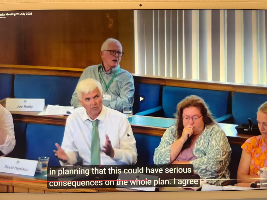 Joe Reilly speaks during a planning meeting, with text overlay about consequences.