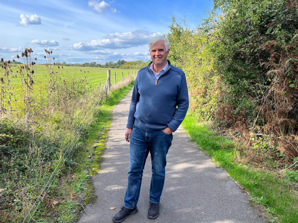 Man in blue sweater and jeans standing on path near Marchwood homes scheme