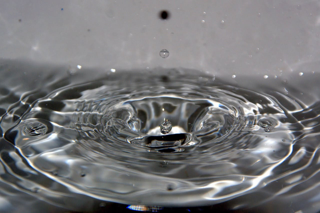 Water droplet creating ripples on a liquid surface, symbolizing a leak.