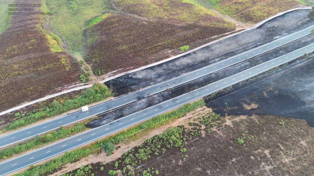 Aerial view of a highway cutting through a burnt landscape in Hampshire