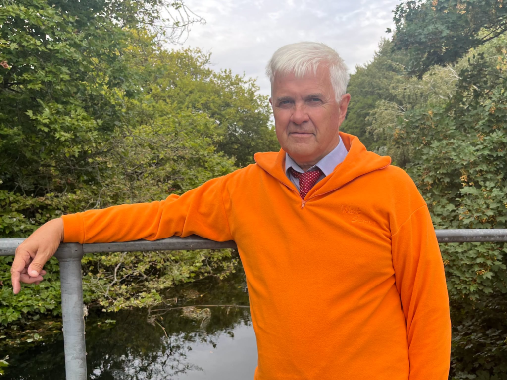 Man in orange hoodie by chalk stream, discussing stream protection