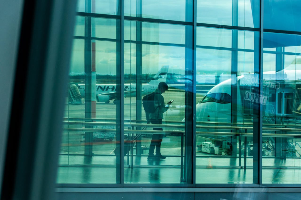 Traveler with luggage at airport gate, boarding a flight for marketing survey.