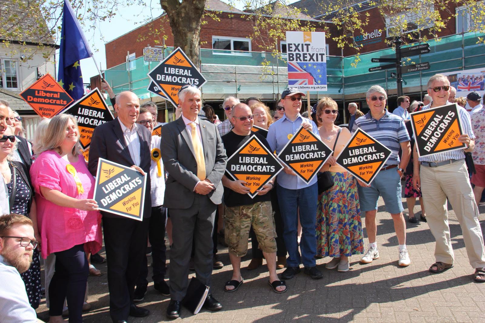 Liberal Democrats rally holding "Working For You" signs, with "Exit from Brexit" banner.