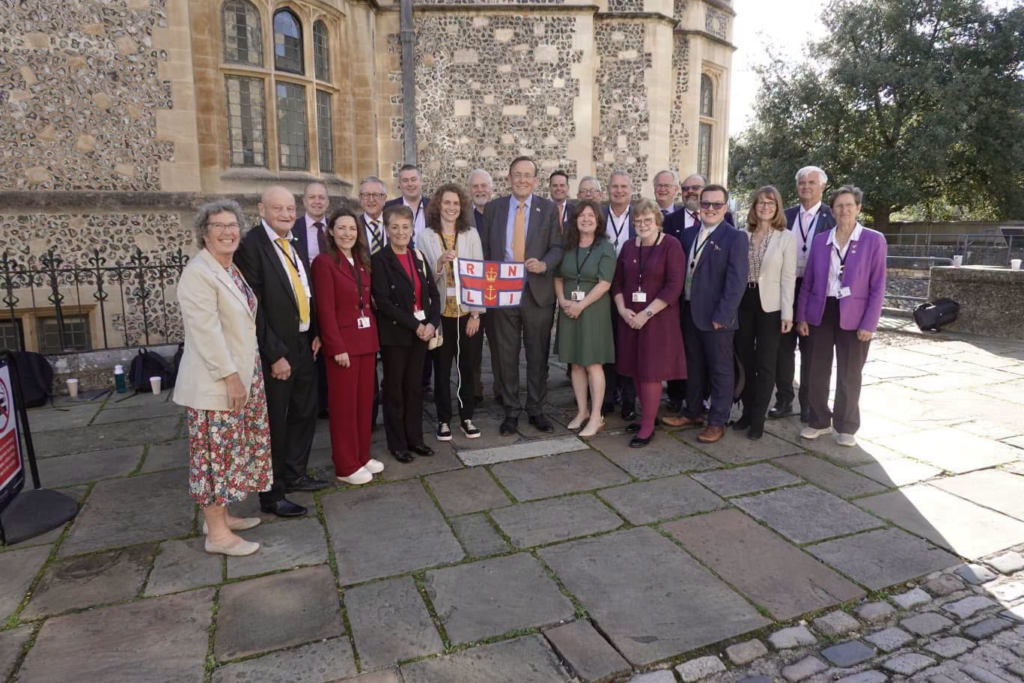 Group poses with RNLI flag outside historic building