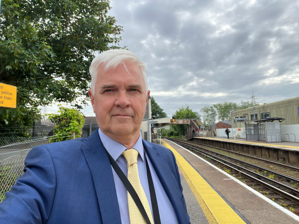 Man in suit at train station platform, waiting for a train.