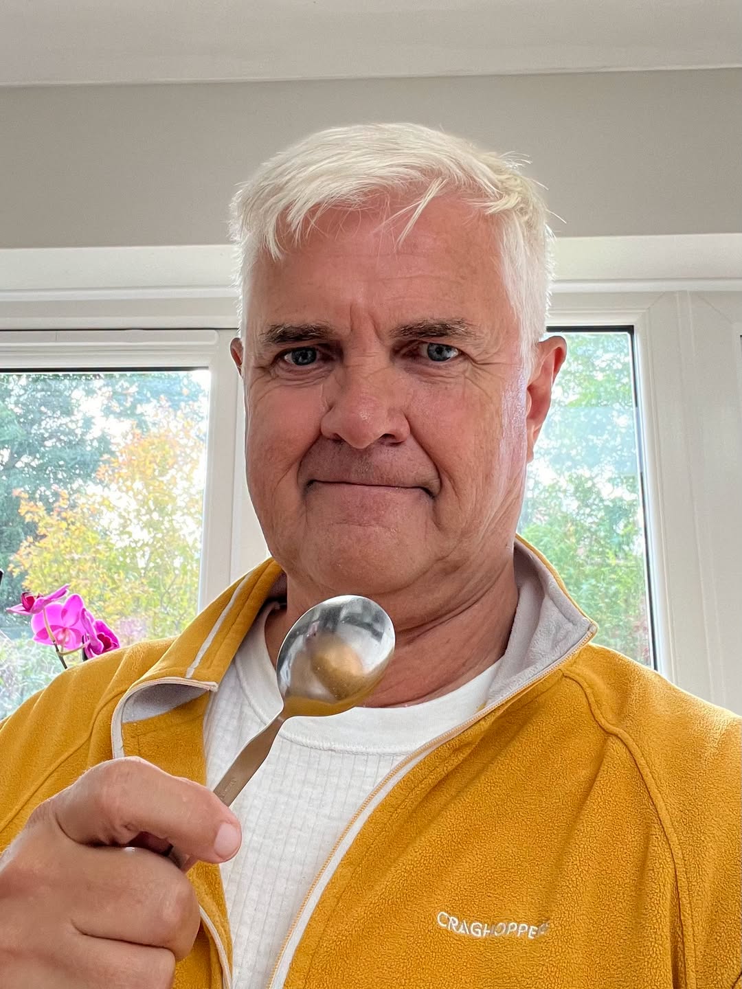 Man in yellow jacket holding a spoon, smiling